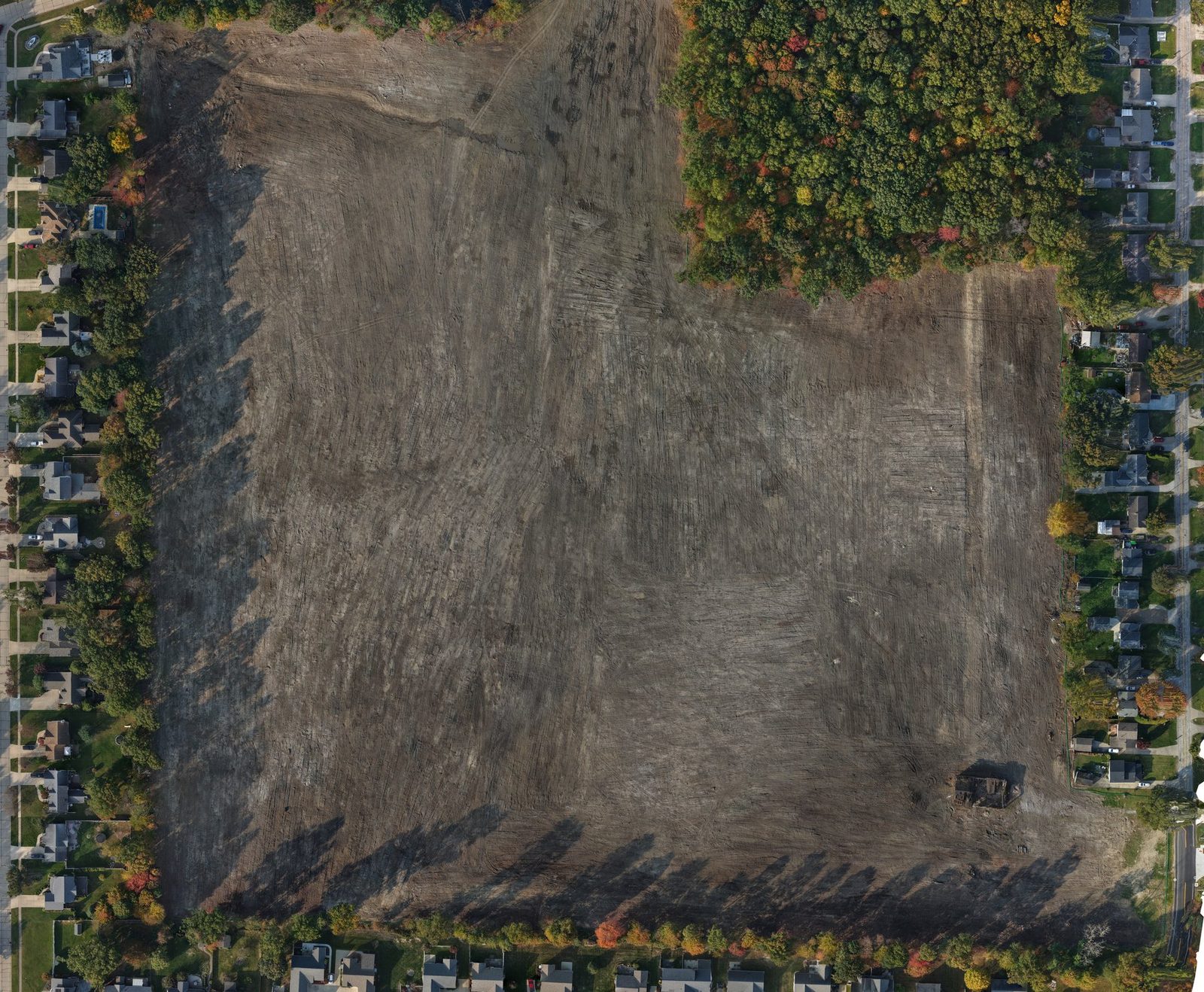 Orthomosaic map of a cleared construction site surrounded by houses and trees